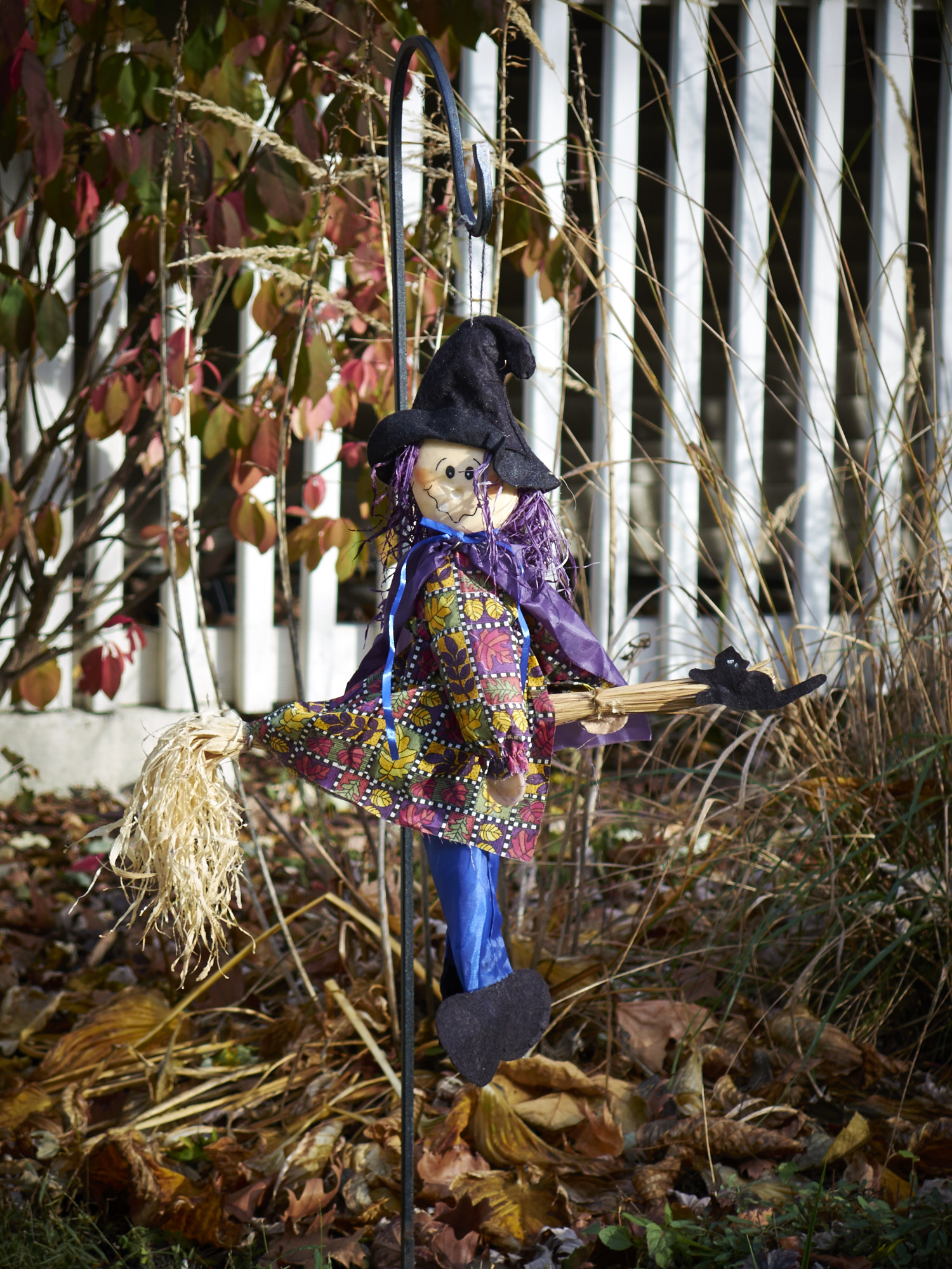 A Halloween scarecrow/witch guards a front lawn